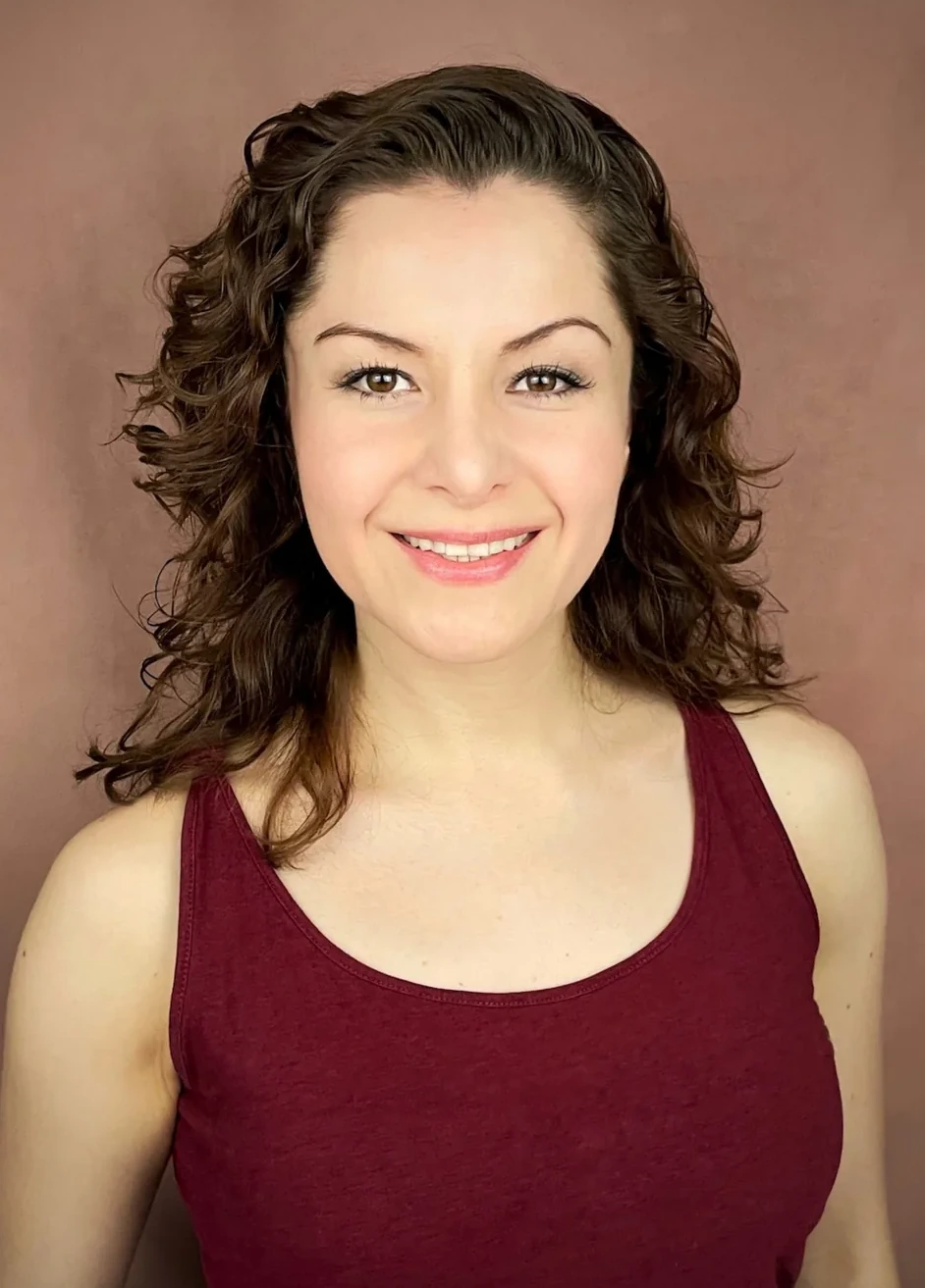 Wendy Lechuga commercial headshot — burgundy tank top, curly hair, warm rose backdrop, friendly smile