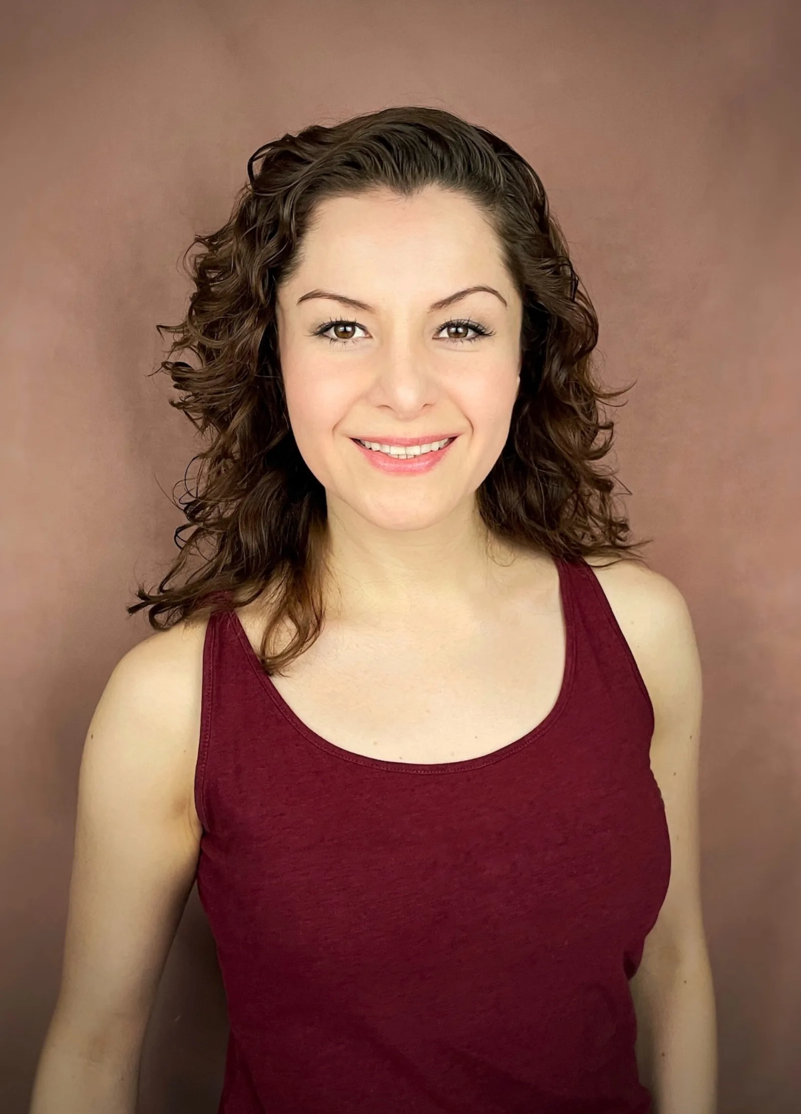 Wendy Lechuga smiling in burgundy tank top against warm rose backdrop — warm commercial portrait